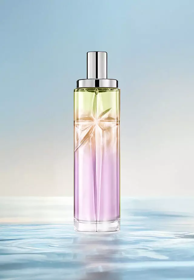 Sweet Kiss Starlicious-recept voor laagjes: hoge flacon met lavendelkleurig, amberkleurig en lichtgroen kleurverloop op water tegen een zachtblauwe achtergrond. Heldere, fruitige geur met een vleugje gourmand; 3 sprays Berry Licorice, 2 Pineapple Musk, 1 Pistachio Praline.