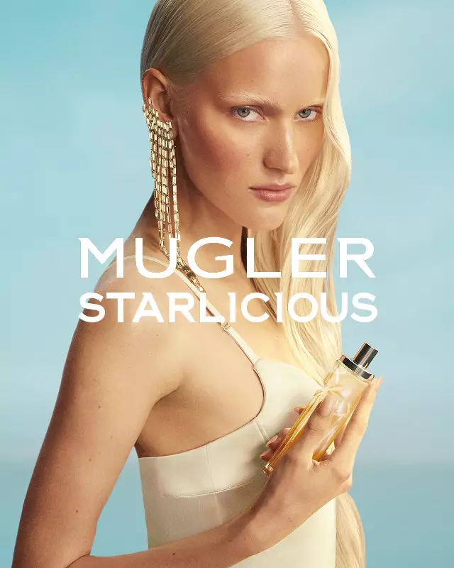 Mugler Starlicious Les Eaux Gourmandes-campagnebanner met model in lichtgele jurk, dat de Pineapple Musk-flacon in de hand houdt tegen een zachtblauwe lucht.