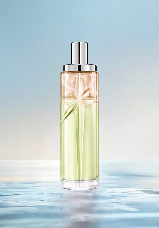 Creamy Delight Starlicious-recept voor laagjes: hoge flacon met groen en amberkleurig kleurverloop op water tegen een zachtblauwe achtergrond. Warme, nootachtige, romige, lichtzoete geur; 2 sprays Pistachio Praline, 1 Pineapple Musk.