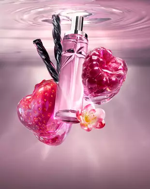 Nieuwe Starlicious Berry Licorice-stilleven met de slanke glazen flacon, omringd door de belangrijkste ingrediënten: een glanzende rode aardbei, een levendige framboos, een delicate roze bloem en gedraaide zwarte zoethoutstokjes, allemaal tegen een zachtroze achtergrond van kabbelend water.