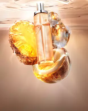 Nieuwe Starlicious Pineapple Musk stilleven met de slanke glazen flacon, omringd door de belangrijkste ingrediënten: een stralende ananasschijf, een gebarsten kokosnootschil en kristallijne muskus, allemaal tegen een warme, stralende achtergrond van kabbelend water.